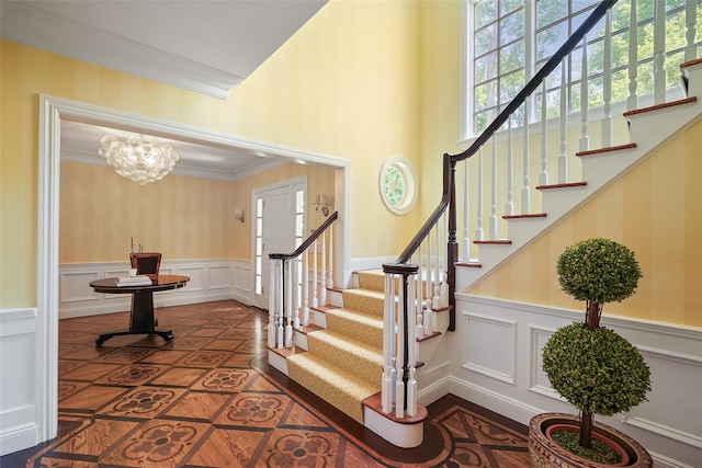 28 Stone Paddock Pl, Bedford, NY 10506 - stairway with inlaid floor details, a decorative wall, a chandelier, a towering ceiling, and wainscoting