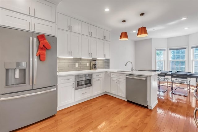 1200 Half Moon Bay Dr, Croton-On-Hudson, NY 10520 - kitchen featuring appliances with stainless steel finishes, light countertops, a peninsula, light wood-style floors, and recessed lighting