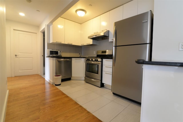 132-35 41st Rd Unit 5D, Flushing, NY 11355 - kitchen with appliances with stainless steel finishes, under cabinet range hood, dark countertops, white cabinets, and recessed lighting