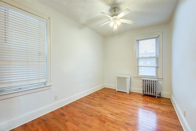 56-20 68th St, Maspeth, NY 11378 - empty room featuring radiator heating unit, radiator, light wood finished floors, a textured ceiling, and ceiling fan