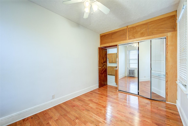 56-20 68th St, Maspeth, NY 11378 - unfurnished bedroom featuring light wood-style floors, a textured ceiling, a closet, a ceiling fan, and radiator