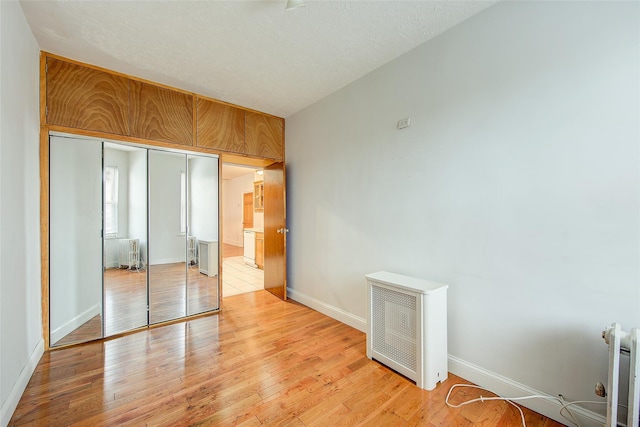 56-20 68th St, Maspeth, NY 11378 - unfurnished bedroom with radiator, light wood-type flooring, and a closet