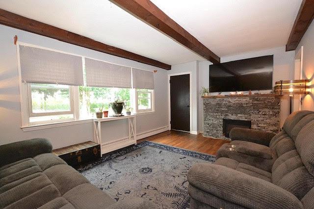 70 Islip Ave, Islip, NY 11751 - living area with beamed ceiling, wood finished floors, a fireplace, and baseboard heating