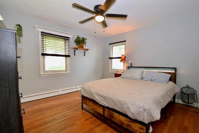 70 Islip Ave, Islip, NY 11751 - bedroom featuring baseboard heating, wood finished floors, and a ceiling fan