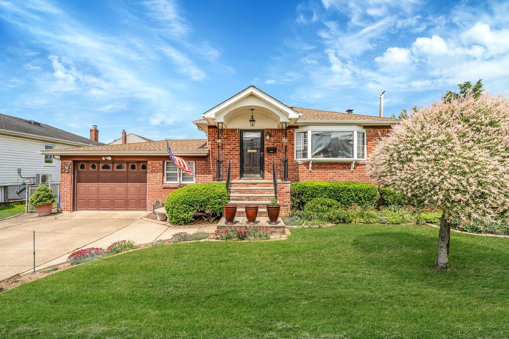 3324 Murdock Ave, Oceanside, NY 11572 - view of front of property with brick siding, driveway, a garage, and a front yard