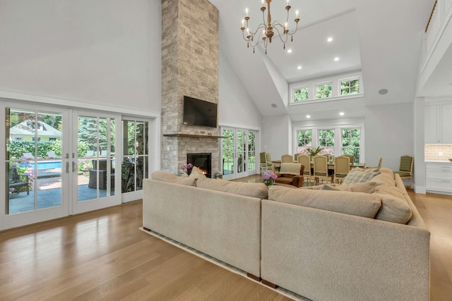 120 Cambon Ave, Saint James, NY 11780 - living room featuring a towering ceiling, light wood-type flooring, a stone fireplace, recessed lighting, and a chandelier