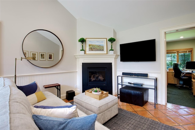 100 Gristmill Ln, Manhasset, NY 11030 - living area featuring a glass covered fireplace, vaulted ceiling, tile patterned floors, and a wainscoted wall
