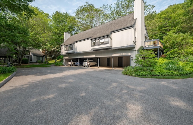 331 Heritage Hls Unit A, Somers, NY 10589 - view of front of property featuring a chimney, a shingled roof, covered parking, and a balcony