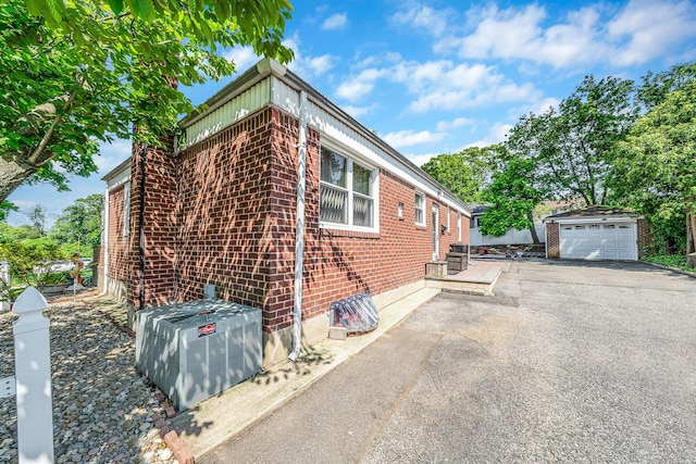 191 Laurel Rd, East Northport, NY 11731 - view of side of home featuring brick siding, a detached garage, driveway, an outdoor structure, and central air condition unit