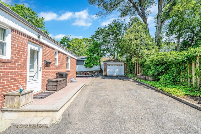 191 Laurel Rd, East Northport, NY 11731 - view of patio featuring asphalt driveway, a garage, and an outbuilding