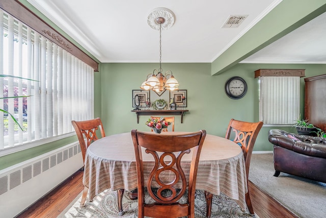 191 Laurel Rd, East Northport, NY 11731 - dining area with radiator heating unit, a chandelier, healthy amount of natural light, crown molding, and wood finished floors