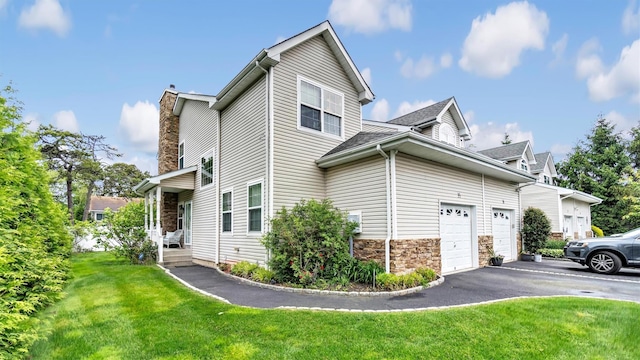 35 Terrace Ln Unit 35, Patchogue, NY 11772 - view of side of property with driveway, a lawn, a chimney, stone siding, and an attached garage