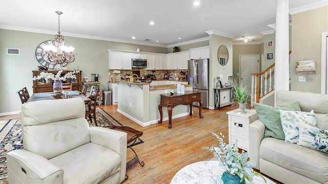 35 Terrace Ln Unit 35, Patchogue, NY 11772 - living area featuring stairway, a chandelier, light wood finished floors, ornamental molding, and recessed lighting
