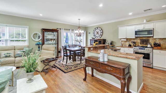 35 Terrace Ln Unit 35, Patchogue, NY 11772 - kitchen with stainless steel appliances, a chandelier, white cabinetry, light wood-style floors, and a breakfast bar