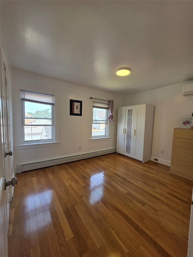 244-59 89th Ave, Bellerose, NY 11426 - unfurnished bedroom featuring a baseboard radiator, hardwood / wood-style floors, and a wall mounted air conditioner