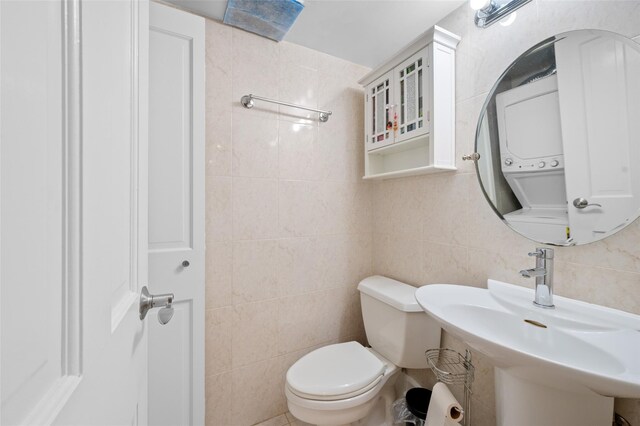 41 Wellington Ct Unit 1L, Staten Island, NY 10314 - bathroom featuring stacked washer / drying machine, tile walls, toilet, and a sink