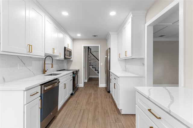 105 Julbet Dr, Sayville, NY 11782 - kitchen featuring appliances with stainless steel finishes, recessed lighting, tasteful backsplash, white cabinets, and light wood-style flooring