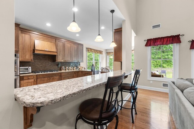 1 Hidden Hills Ct, Warwick, NY 10990 - kitchen featuring custom exhaust hood, light wood-style flooring, a kitchen bar, brown cabinets, and stainless steel gas stovetop
