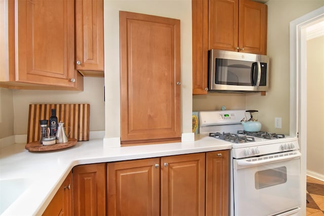 1360 Midland Ave Unit 1B, Bronxville, NY 10708 - kitchen with stainless steel microwave, white gas stove, brown cabinetry, and light countertops