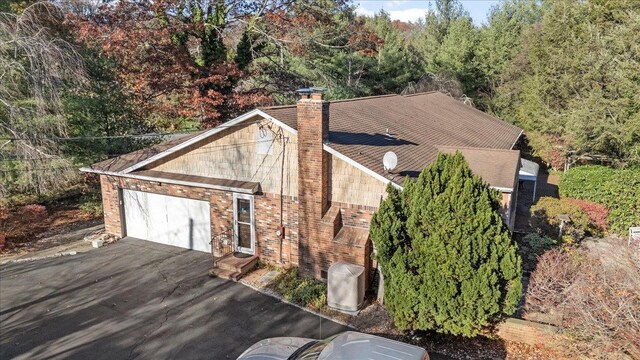 175 Laurel Ln, Laurel Hollow, NY 11791 - view of property exterior featuring a chimney, asphalt driveway, a view of trees, and a garage