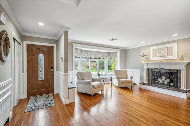 86 Phipps Ln, Plainview, NY 11803 - entrance foyer with wood finished floors, a decorative wall, a fireplace with raised hearth, ornamental molding, and a wainscoted wall