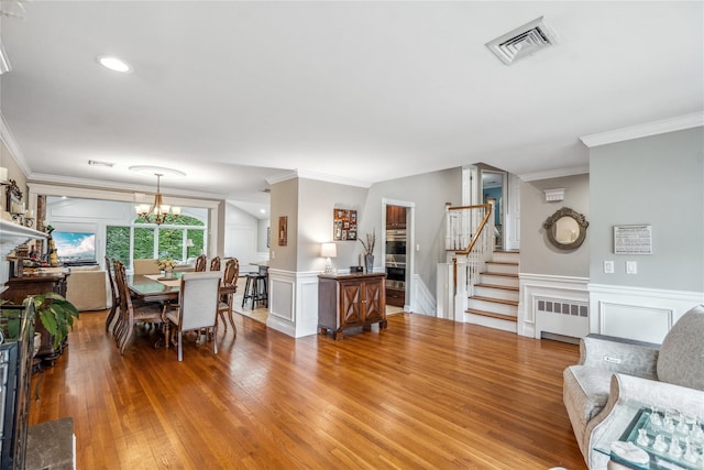 86 Phipps Ln, Plainview, NY 11803 - dining room with radiator heating unit, stairs, crown molding, wood finished floors, and a chandelier