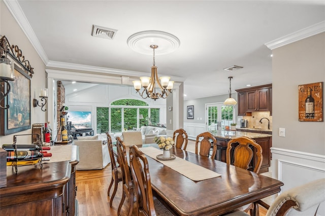 86 Phipps Ln, Plainview, NY 11803 - dining area with a decorative wall, crown molding, a chandelier, light wood-type flooring, and a wainscoted wall