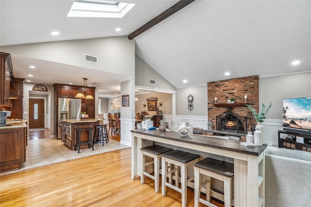 86 Phipps Ln, Plainview, NY 11803 - kitchen featuring open floor plan, high end refrigerator, a skylight, a kitchen island, and a kitchen bar