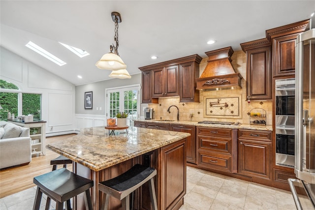 86 Phipps Ln, Plainview, NY 11803 - kitchen featuring custom exhaust hood, a skylight, a baseboard radiator, backsplash, and a decorative wall