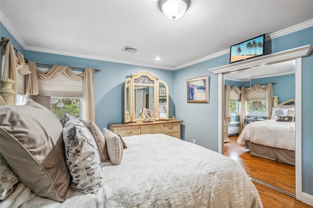86 Phipps Ln, Plainview, NY 11803 - bedroom with wood finished floors, multiple windows, ornamental molding, radiator heating unit, and recessed lighting