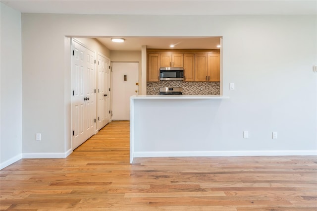 255 Country Club Ln, Pomona, NY 10970 - kitchen with appliances with stainless steel finishes, light wood finished floors, light countertops, decorative backsplash, and brown cabinetry