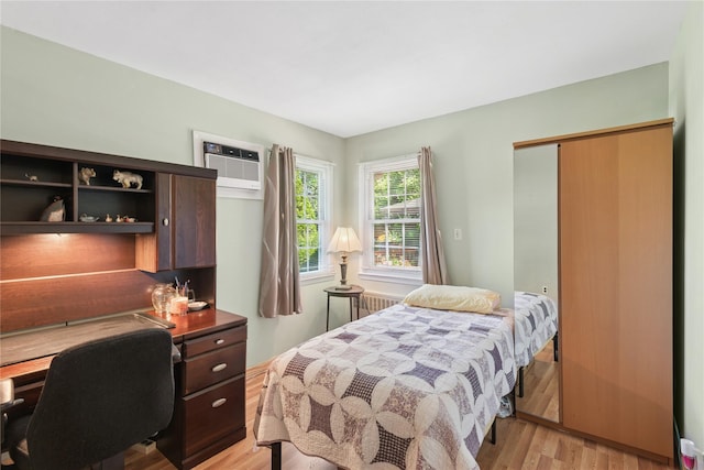 6 Grey Rock Ct, Bethpage, NY 11714 - bedroom with a wall mounted air conditioner, light wood-style floors, radiator, a closet, and a desk