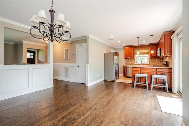 56 Lakeland Ave, Babylon, NY 11702 - kitchen featuring appliances with stainless steel finishes, light countertops, brown cabinetry, a chandelier, and backsplash