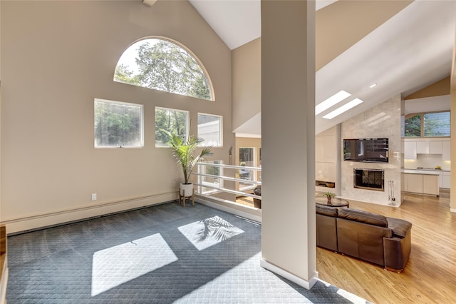 64 Highland Ave, Roslyn, NY 11576 - living area featuring baseboard heating, a skylight, high vaulted ceiling, wood finished floors, and a fireplace