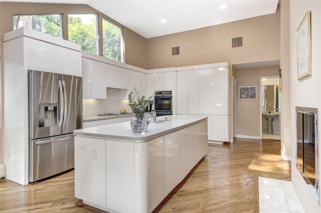 64 Highland Ave, Roslyn, NY 11576 - kitchen with stainless steel appliances, high vaulted ceiling, modern cabinets, white cabinets, and light countertops
