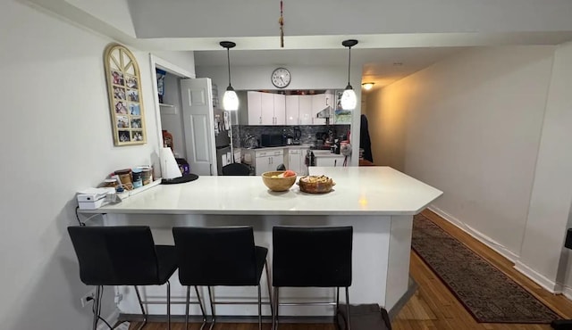 65-39 108th St Unit E6, Forest Hills, NY 11375 - kitchen with a peninsula, dark wood finished floors, white cabinetry, backsplash, and hanging light fixtures