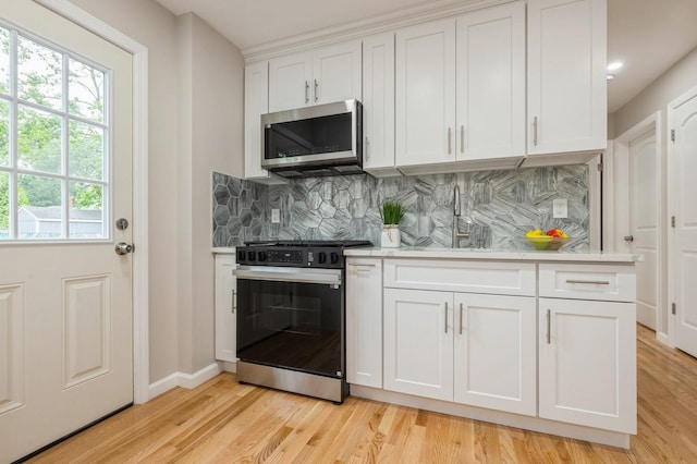 1086 Lehman Rd, West Hempstead, NY 11552 - kitchen with stainless steel microwave, black range with electric stovetop, light countertops, decorative backsplash, and white cabinetry