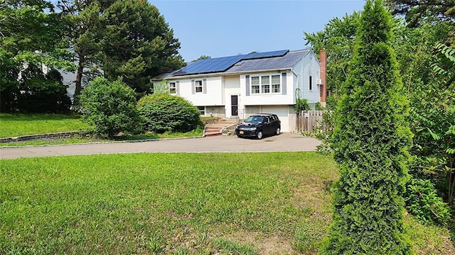 663 N Dunton Ave, East Patchogue, NY 11772 - split foyer home featuring driveway, solar panels, a front yard, a chimney, and a garage