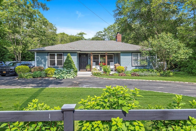 135 Vanderbilt Blvd, Oakdale, NY 11769 - view of front of house featuring a chimney, covered porch, a front yard, and a shingled roof