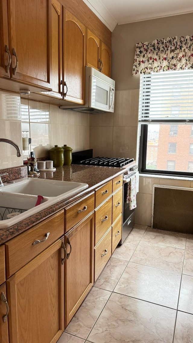 99-05 63rd Dr Unit 11Aa, Rego Park, NY 11374 - kitchen with white microwave, gas range, brown cabinetry, dark countertops, and backsplash
