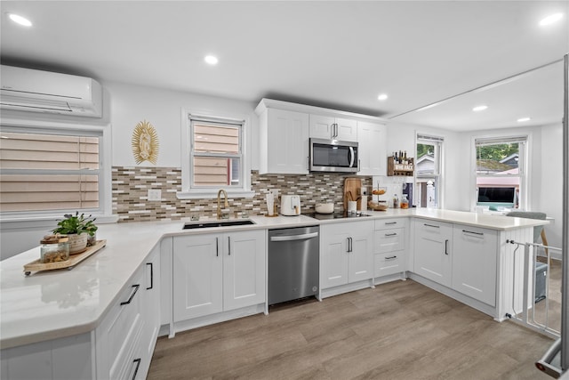 3234 204th St, Bayside, NY 11361 - kitchen with appliances with stainless steel finishes, a peninsula, a wall mounted air conditioner, light wood-type flooring, and decorative backsplash