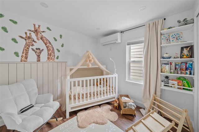 3234 204th St, Bayside, NY 11361 - bedroom featuring an AC wall unit, a nursery area, and wood finished floors