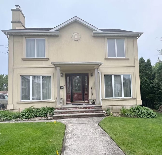 65 Netherwood Dr, Albertson, NY 11507 - view of front of house featuring a chimney, a front yard, and stucco siding