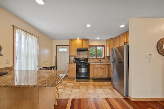 65 Netherwood Dr, Albertson, NY 11507 - kitchen featuring freestanding refrigerator, black range with gas stovetop, under cabinet range hood, dark stone countertops, and tasteful backsplash