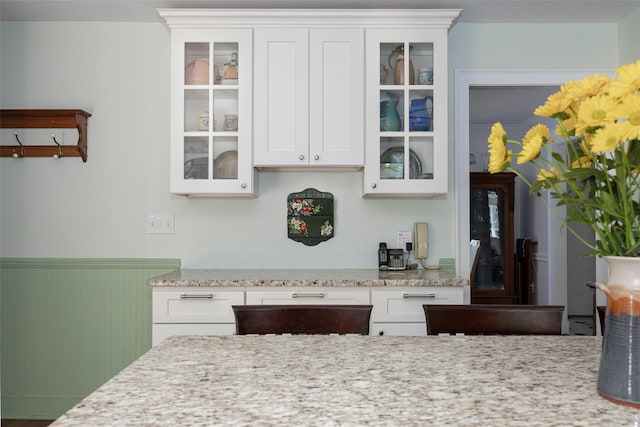4 Tower Rd, Hopewell Junction, NY 12533 - kitchen featuring a wainscoted wall, glass insert cabinets, white cabinets, and light stone counters