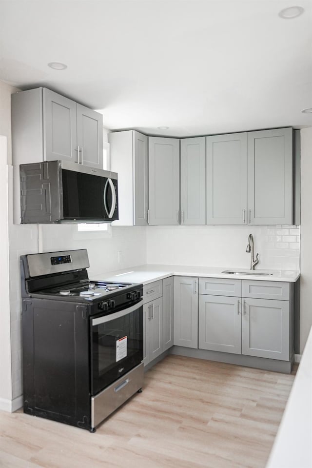 8620 130th St, Richmond Hill, NY 11418 - kitchen with gas range, stainless steel microwave, gray cabinets, and light wood-type flooring