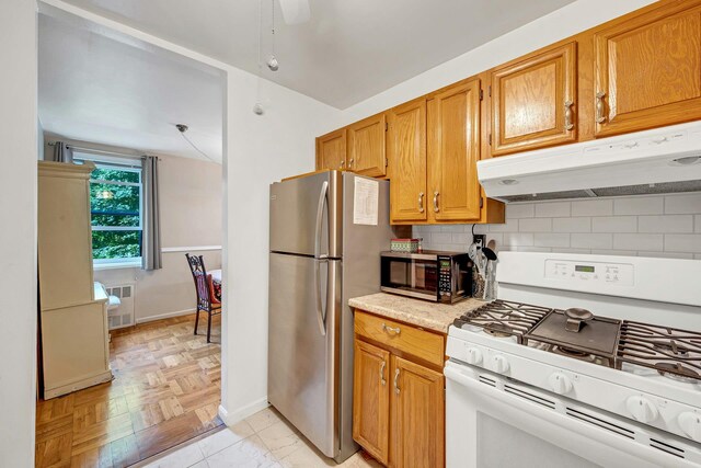 98 Dehaven Dr Unit 1F, Yonkers, NY 10703 - kitchen with appliances with stainless steel finishes, under cabinet range hood, light countertops, decorative backsplash, and brown cabinets