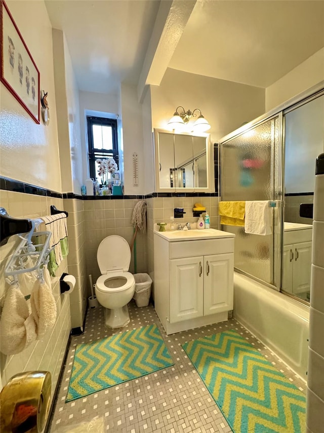 37-27 86th St Unit 3D, Flushing, NY 11372 - bathroom featuring tile walls, vanity, bath / shower combo with glass door, wainscoting, and tile patterned floors