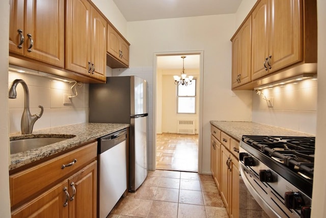 10 Lake St Unit 4E, White Plains, NY 10603 - kitchen with appliances with stainless steel finishes, radiator, backsplash, light stone countertops, and a chandelier