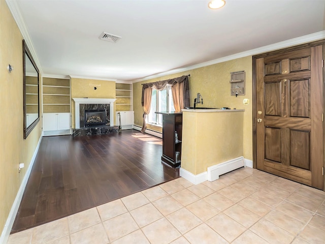 1 Barry Dr, Glen Cove, NY 11542 - foyer entrance featuring a baseboard radiator, a fireplace with raised hearth, wood finished floors, and crown molding